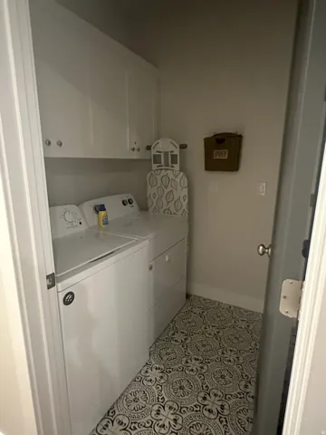 Laundry area featuring cabinet space, washer and dryer, and light tile patterned floors