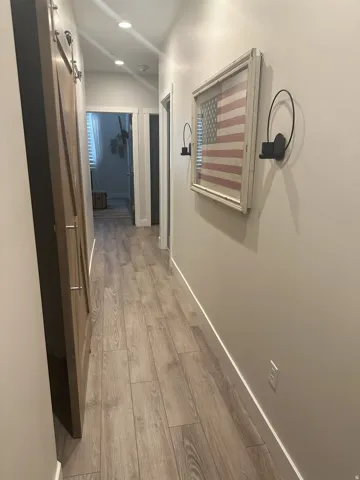 Hallway featuring light wood-type flooring, recessed lighting, and a barn door