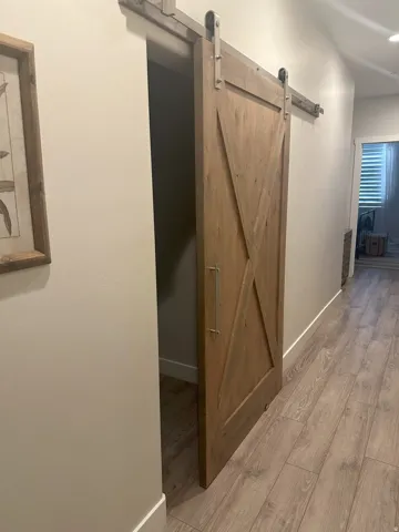 Hall featuring light wood finished floors and a barn door