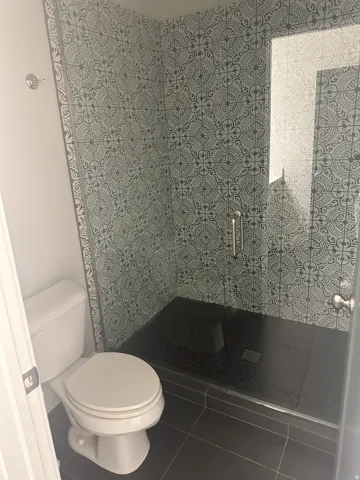 Bathroom featuring dark tile patterned flooring and tiled shower
