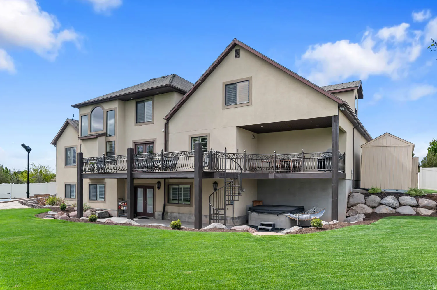 Back of house featuring a hot tub, stucco siding, a patio area, and french doors