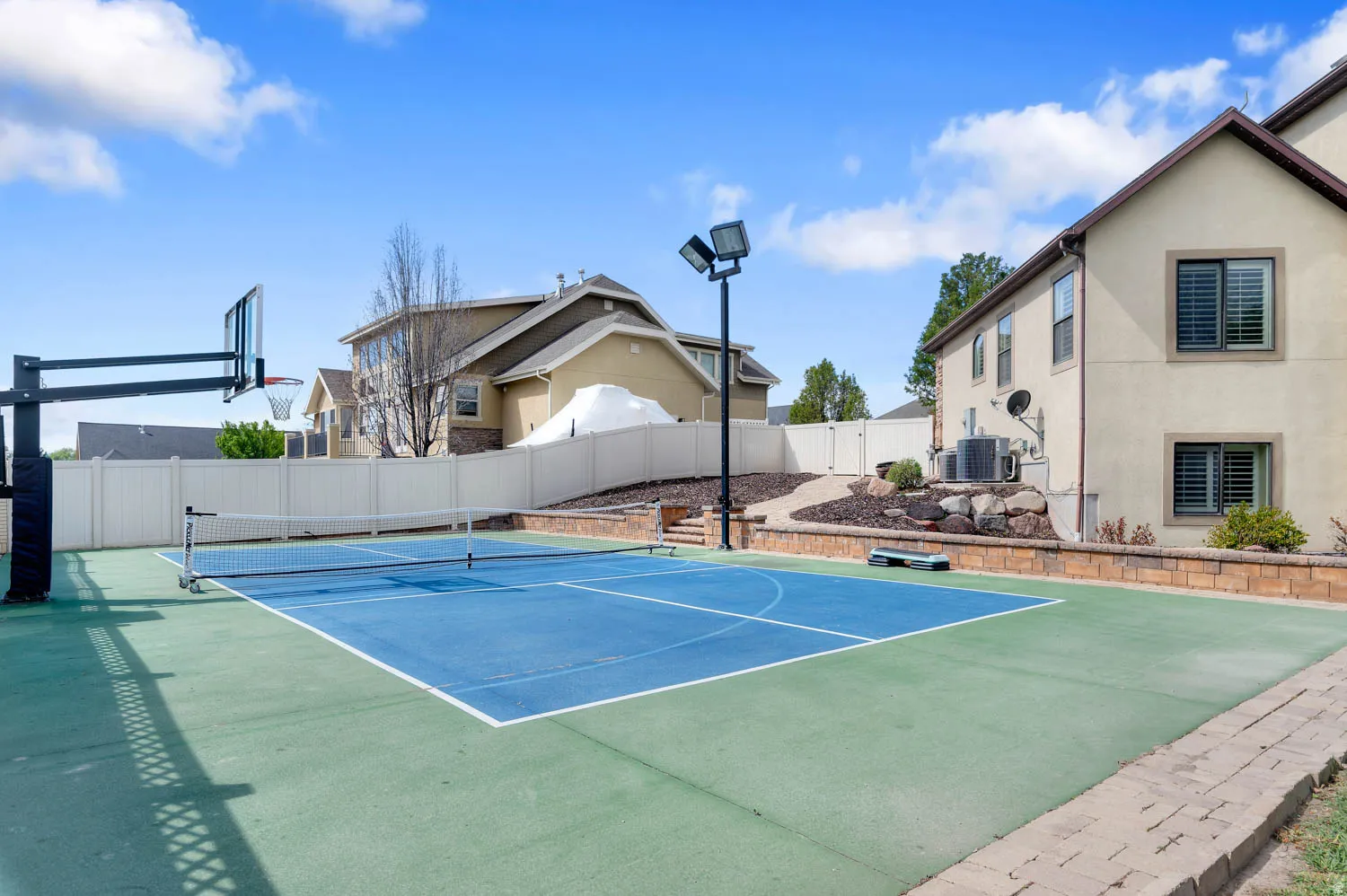 View of tennis court with basketball court and a gate