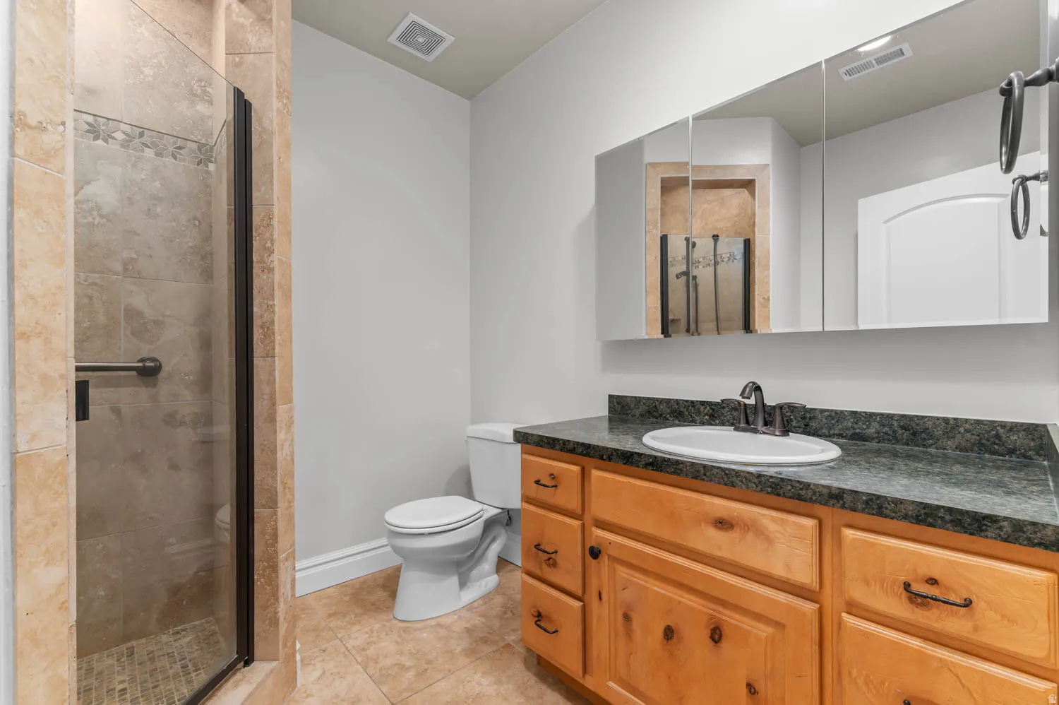 Full bath with vanity, a stall shower, and light tile patterned floors