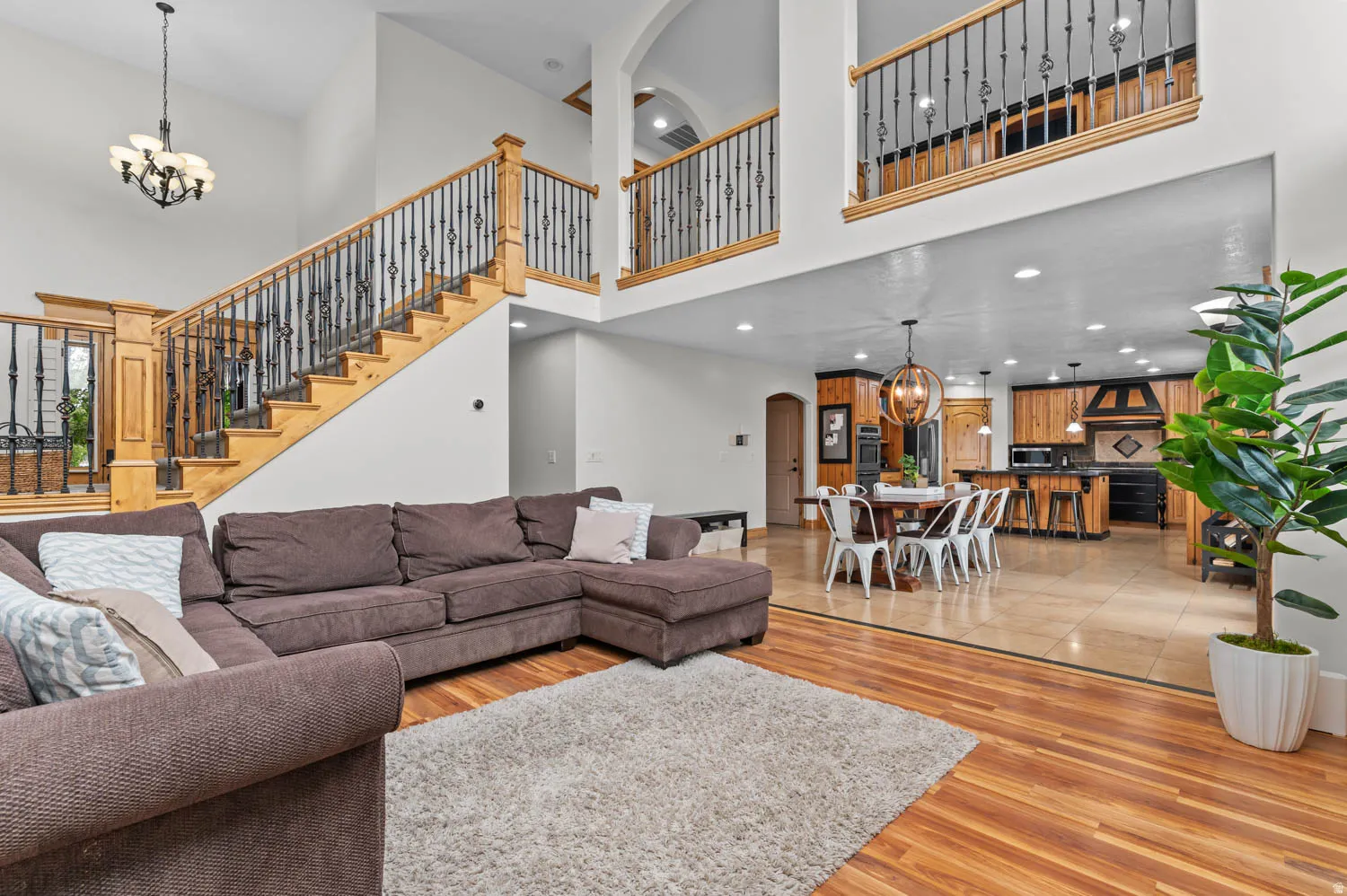 Living room featuring hanging lights, arched walkways, light wood-type flooring, and a high ceiling
