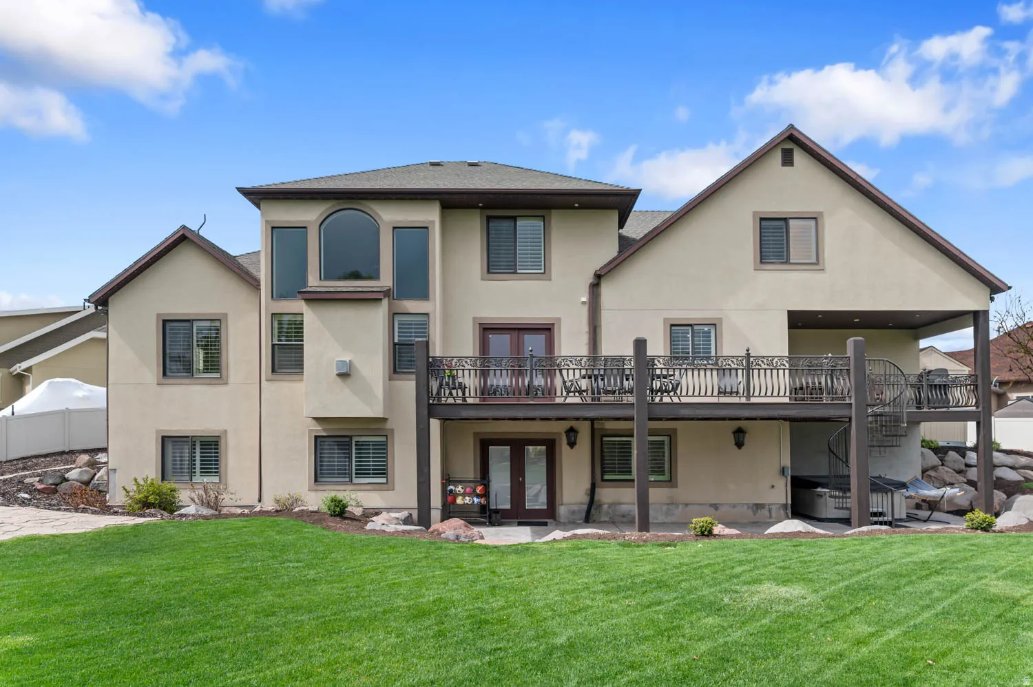 Rear view of house featuring stucco siding, french doors, a lawn, and a patio area