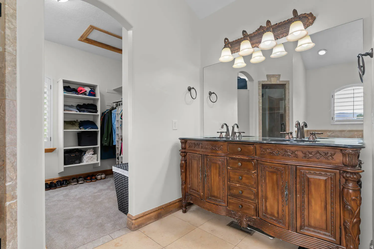 Bathroom featuring double vanity, a spacious closet, light tile patterned floors, and light carpet