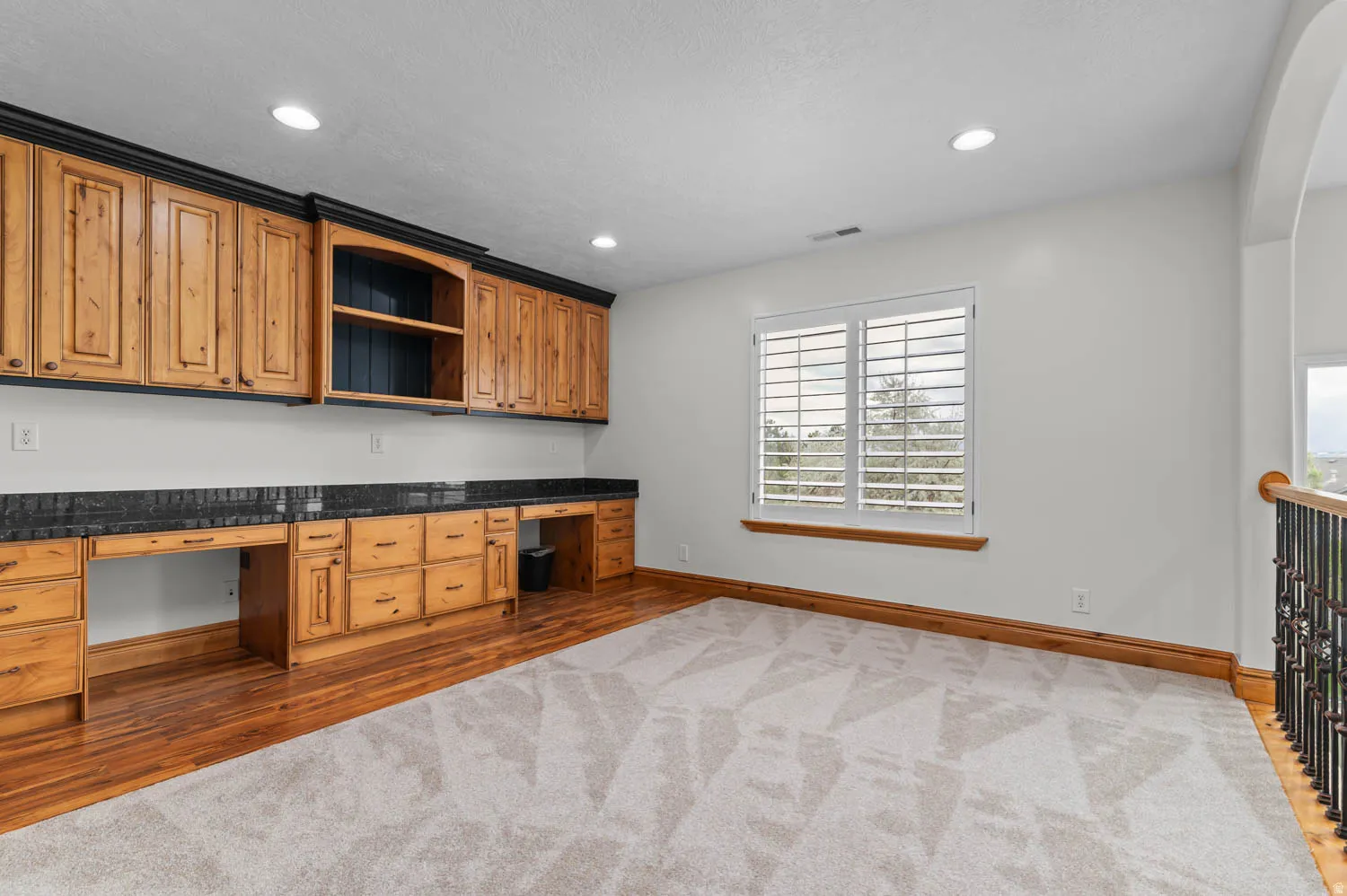 Office area with built in desk, dark wood-style flooring, recessed lighting, and dark carpet