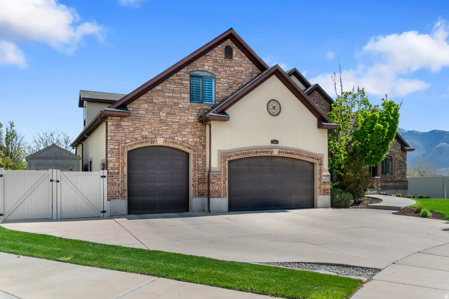 French country style house featuring a gate, stone siding, stucco siding, and concrete driveway