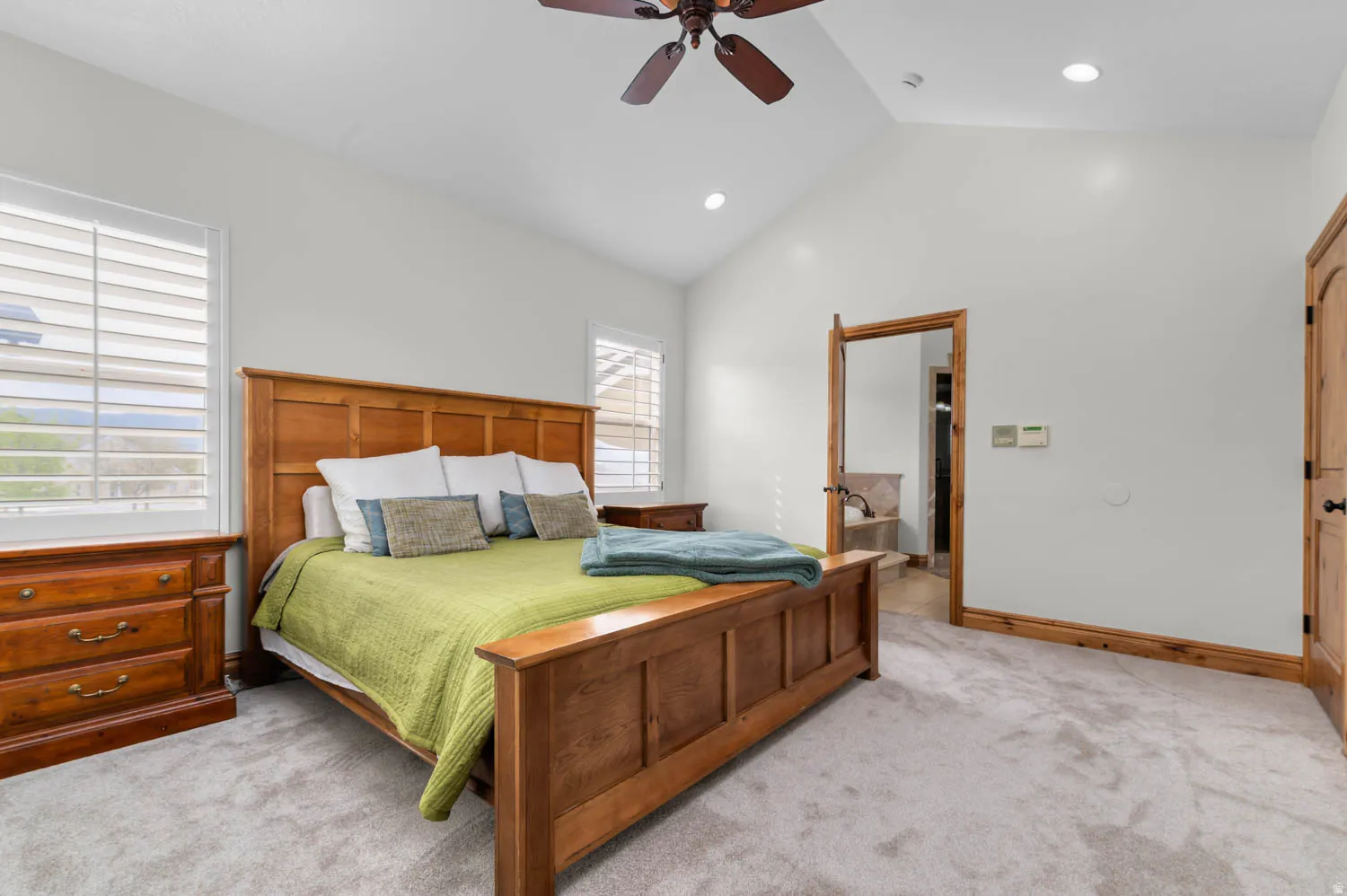 Carpeted bedroom featuring ceiling fan, recessed lighting, a high ceiling, and ensuite bathroom