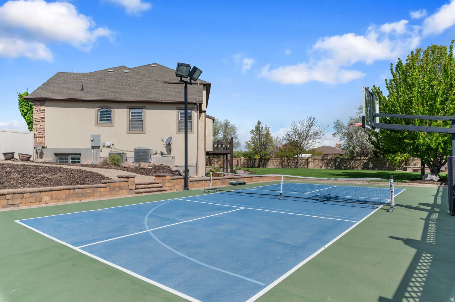 View of tennis court featuring community basketball court and a patio