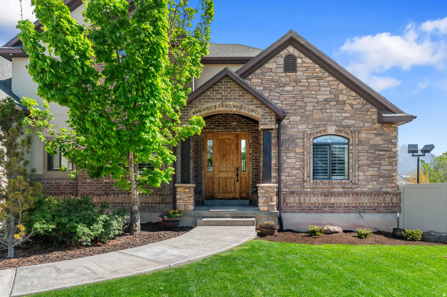 View of front of home featuring stone siding, a front yard, brick siding, and stucco siding