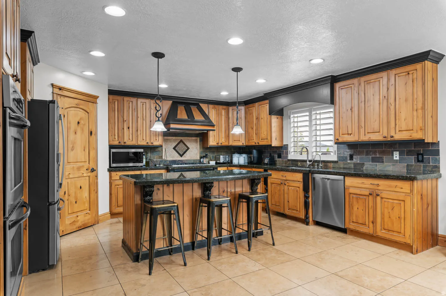 Kitchen featuring a kitchen bar, a center island, pendant lighting, stainless steel appliances, and light tile patterned floors