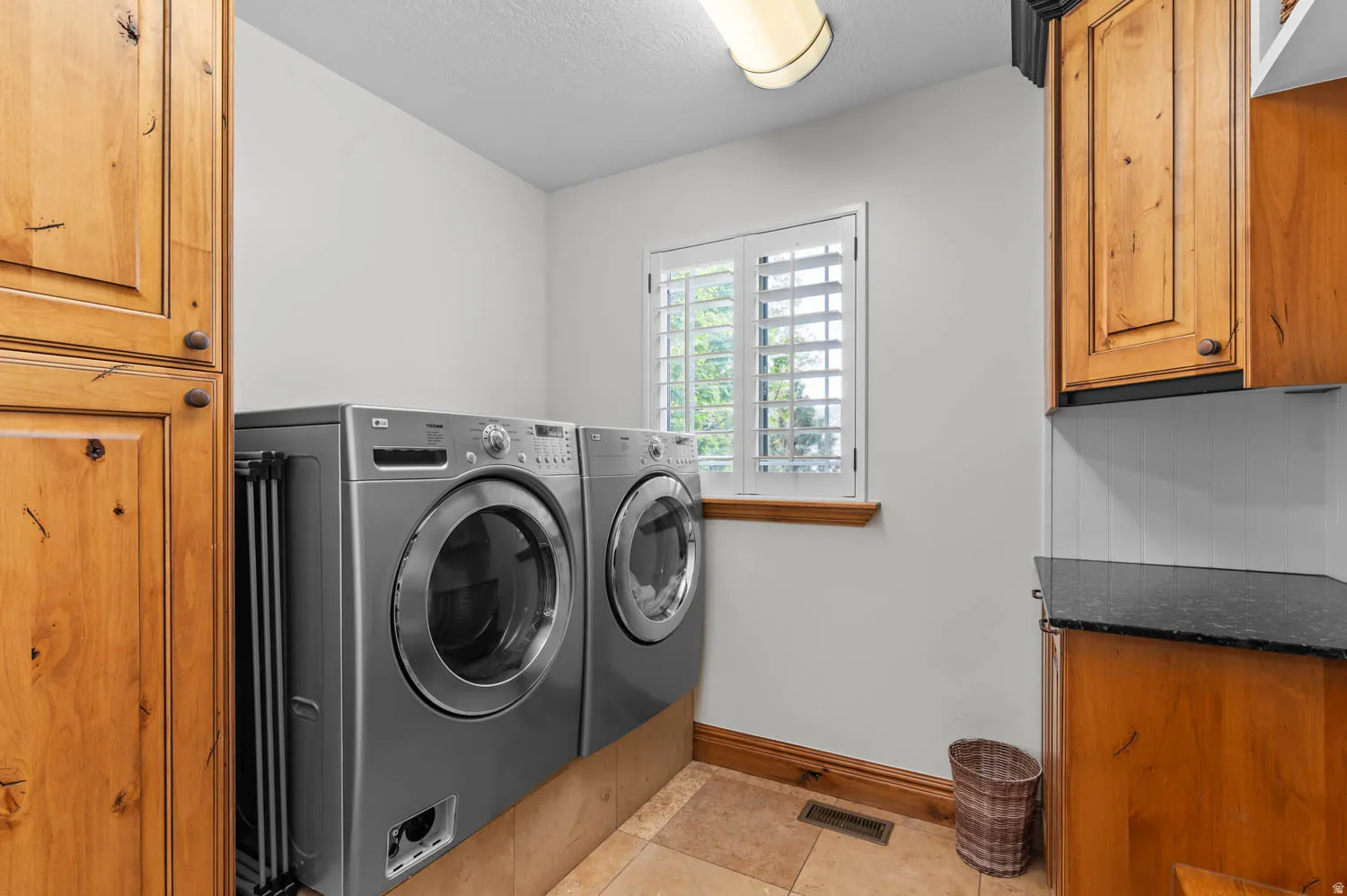Laundry room with cabinet space, washing machine and dryer, a textured ceiling, and light tile patterned floors