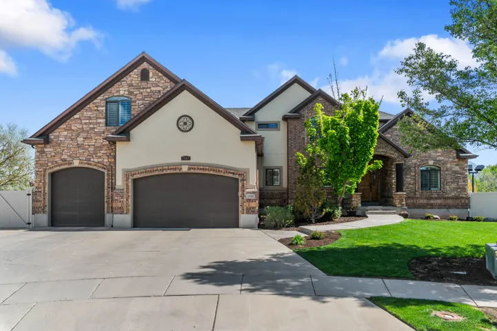 French country style house featuring driveway, stucco siding, a gate, and stone siding