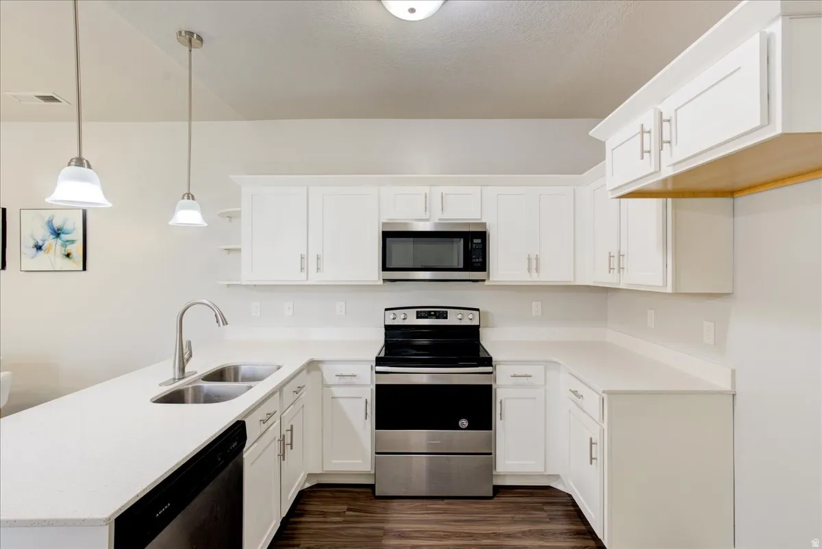 Kitchen featuring stainless steel appliances, a peninsula, decorative light fixtures, white cabinets, and open shelves