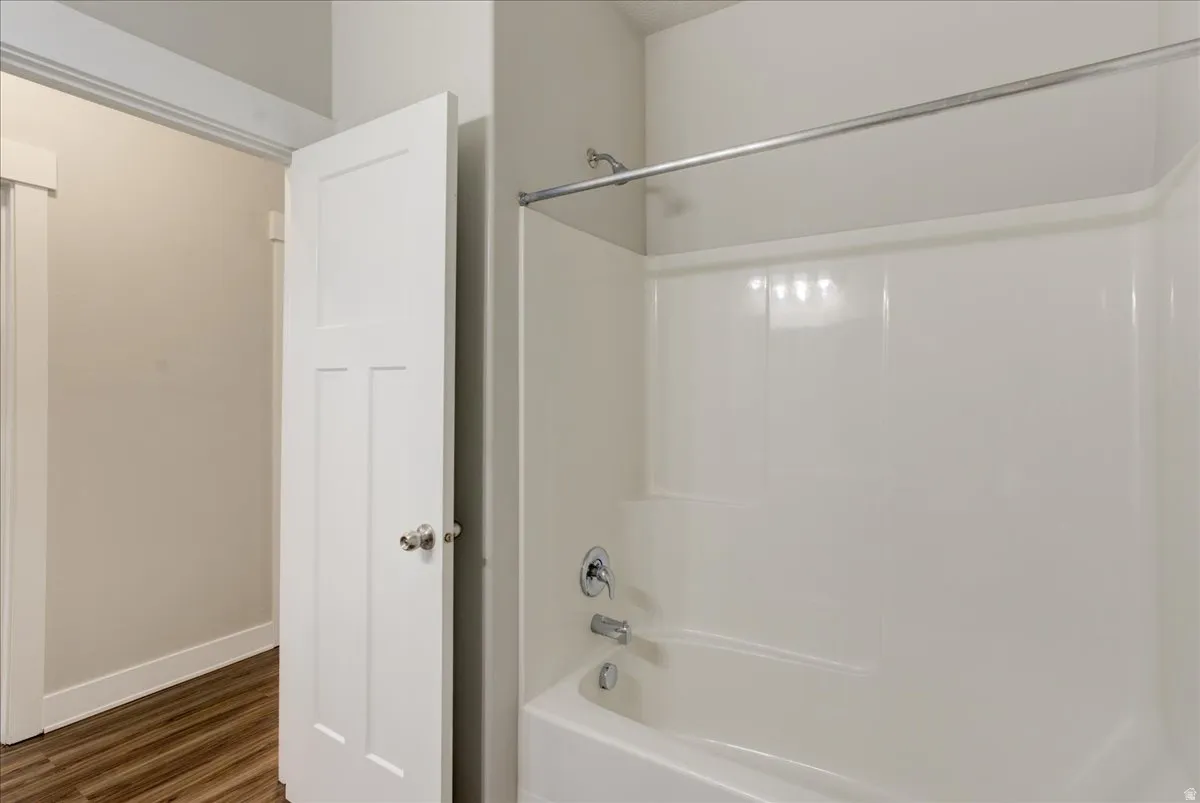 Full bath featuring shower / tub combination and dark wood-style floors