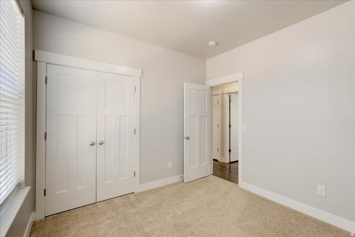 Unfurnished bedroom with light colored carpet and a closet