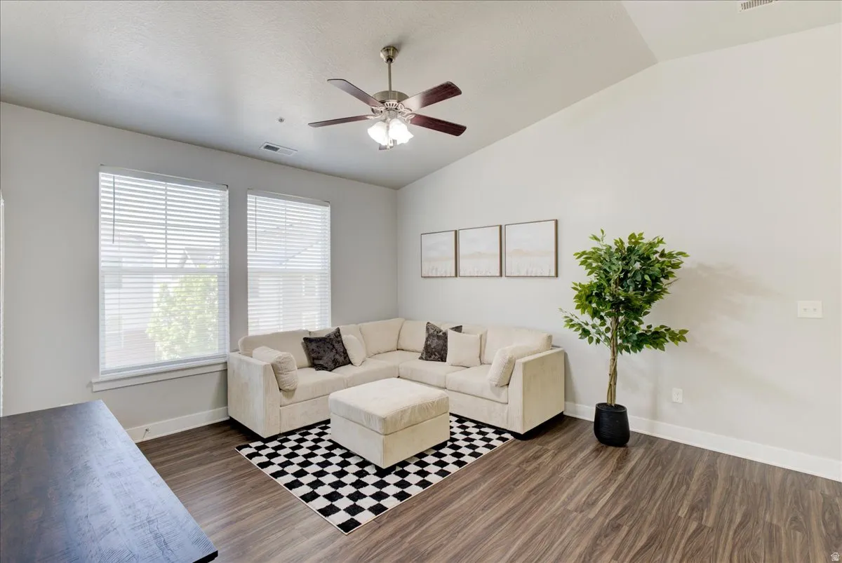 Living area featuring a ceiling fan, lofted ceiling, and dark wood-style floors