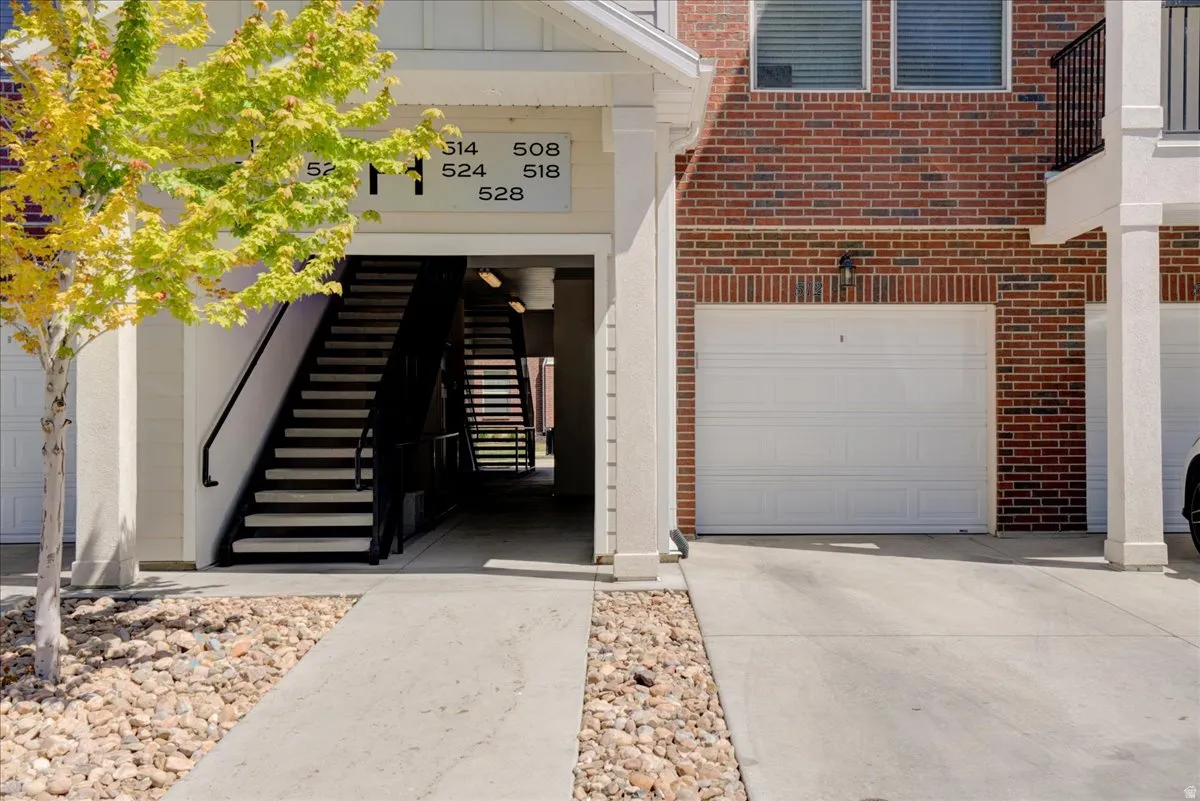 Property entrance with a garage, brick siding, driveway, and board and batten siding