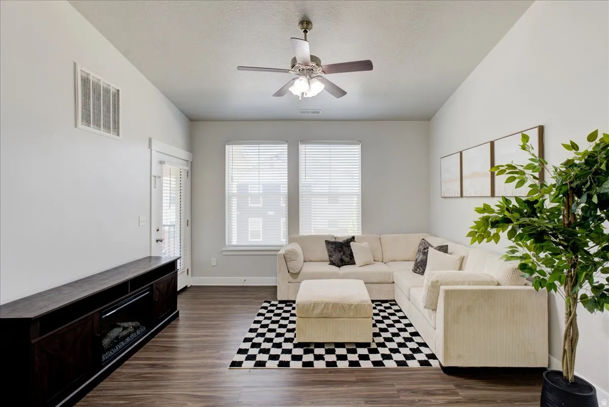 Living area featuring a ceiling fan, dark wood-type flooring, and a textured ceiling