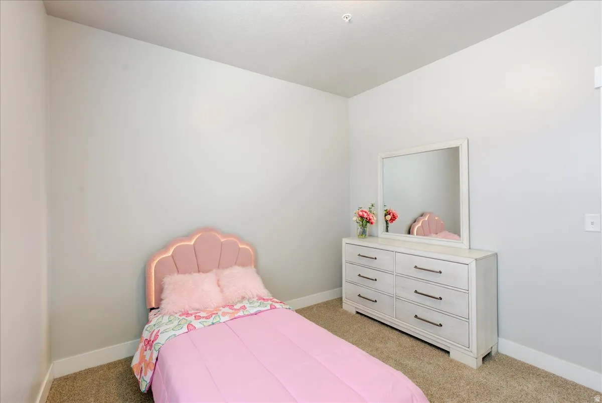 Bedroom with baseboards and light carpet