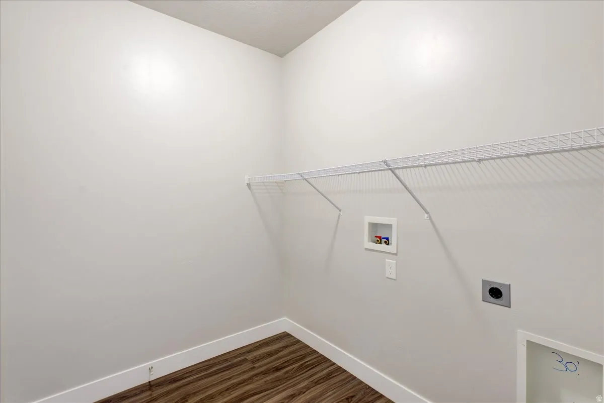 Laundry room with dark wood-type flooring, hookup for a washing machine, and hookup for an electric dryer