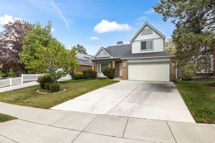 Traditional-style house featuring driveway, brick siding, a porch, an attached garage, and a shingled roof