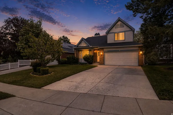 Traditional-style house with a front lawn, driveway, brick siding, and an attached garage