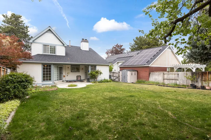 Back of house with a storage shed, a chimney, a patio area, and a fenced backyard