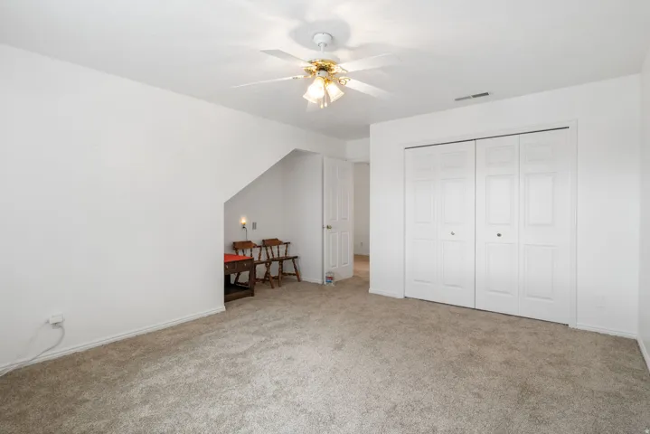 Carpeted bedroom with a closet and ceiling fan