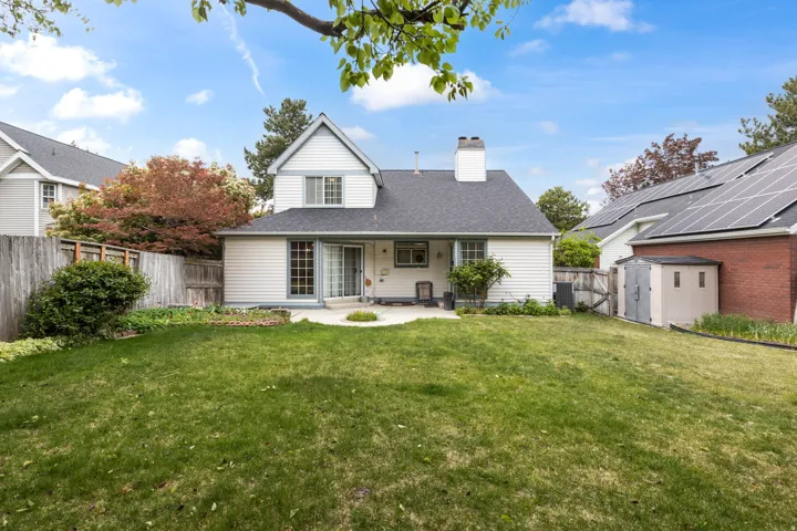 Rear view of house featuring a storage shed, a patio, a chimney, a fenced backyard, and a shingled roof