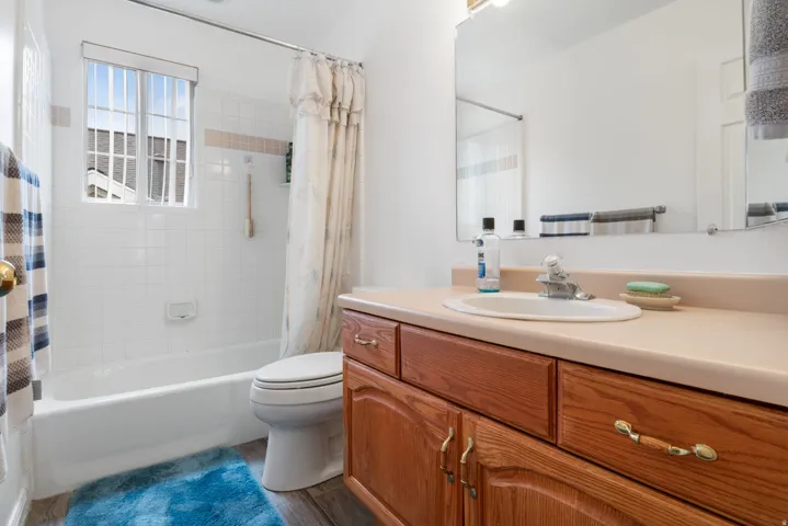 Full bathroom featuring vanity, shower / bathtub combination with curtain, and dark wood-type flooring