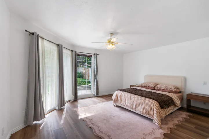 Wood-finish flooring throughout, ceiling fan with light fixture, and double glass doors opening to the exterior