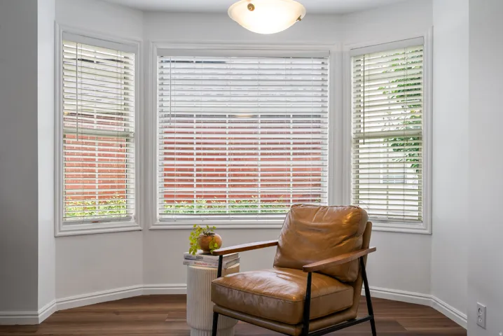 Bay window with blinds, wood-finish flooring, and a semi-flush mount ceiling fixture