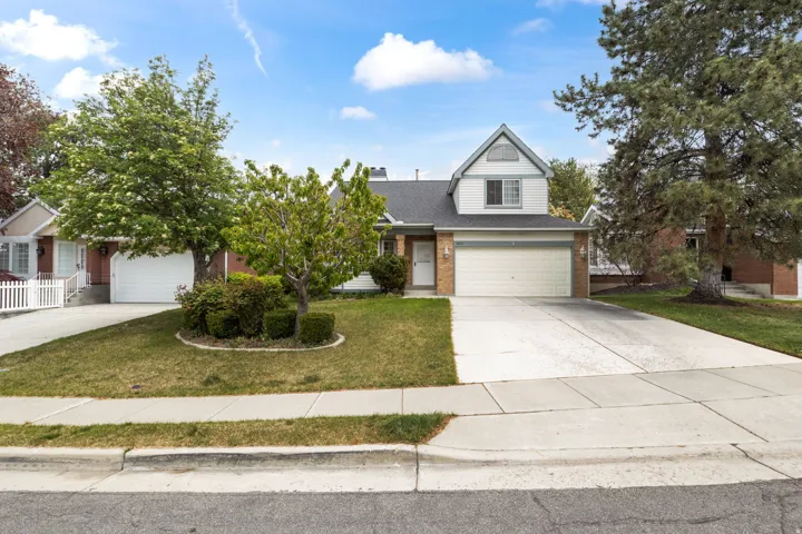 Traditional home with brick siding, a front yard, driveway, a shingled roof, and a garage