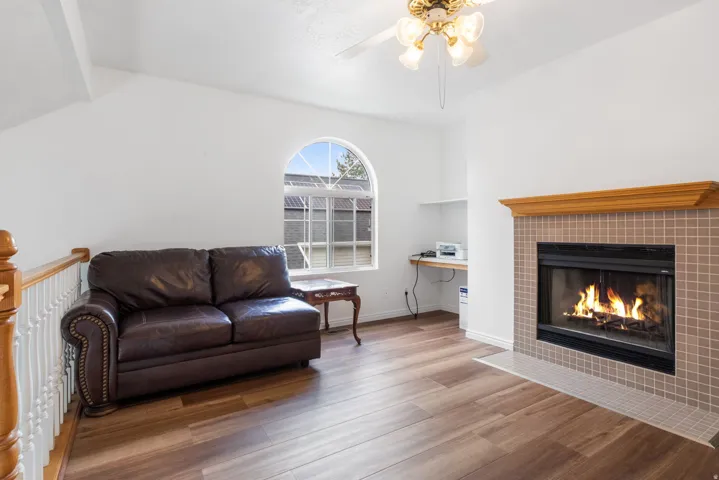 Living room featuring laminate wood finished floors, a ceiling fan, and a tile fireplace