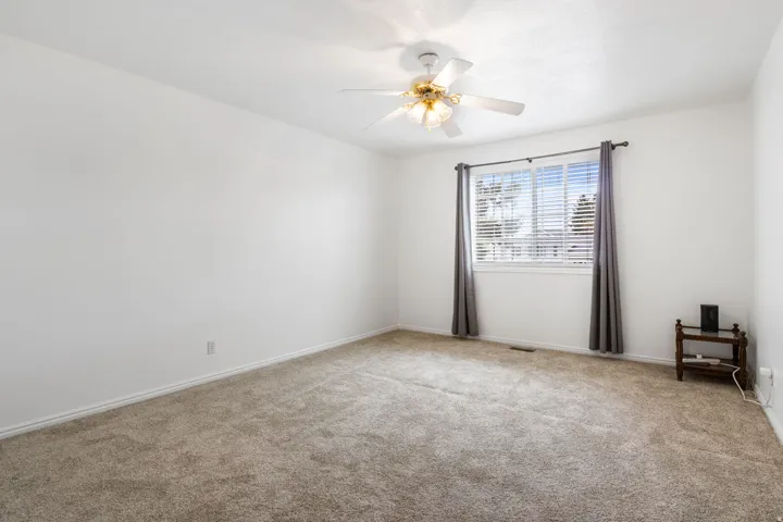 Carpeted empty room with ceiling fan and baseboards