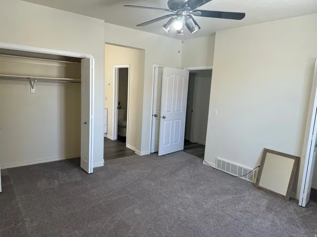 Unfurnished bedroom featuring dark carpet, a closet, and ceiling fan