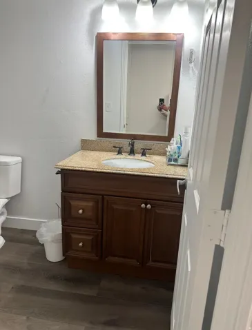 Half bathroom with a textured wall, vanity, and dark wood-type flooring