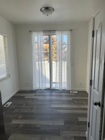 Empty room with dark wood-style flooring and healthy amount of natural light