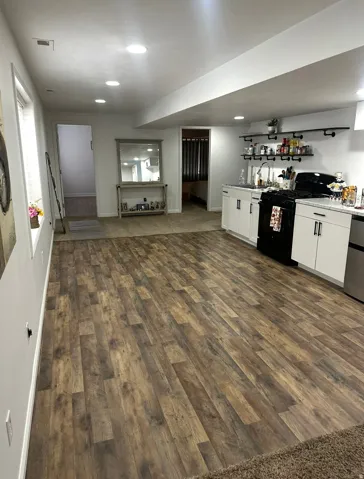 Indoor wet bar with dark wood-type flooring, white cabinets, gas stove, light countertops, and stainless steel refrigerator