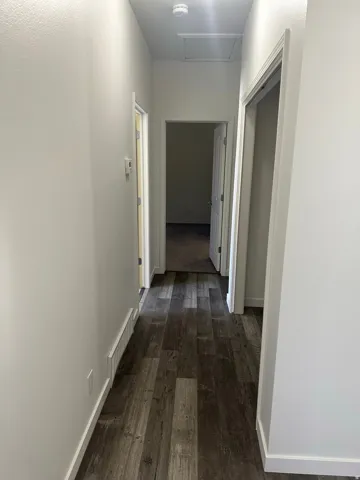Hallway with dark wood-style flooring and baseboards