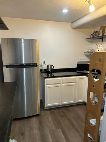 Kitchen featuring stainless steel appliances, white cabinets, dark countertops, a textured ceiling, and dark wood-style flooring