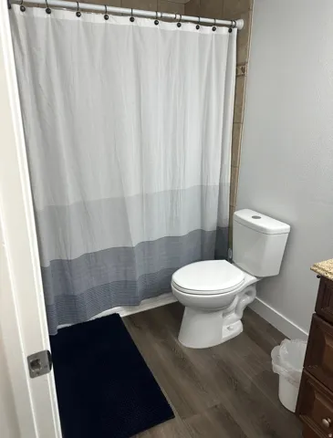 Bathroom featuring vanity, dark wood finished floors, curtained shower, and a textured wall