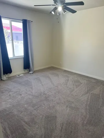 Unfurnished room featuring ceiling fan and carpet flooring