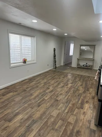 Unfurnished living room with dark wood-type flooring, plenty of natural light, and recessed lighting