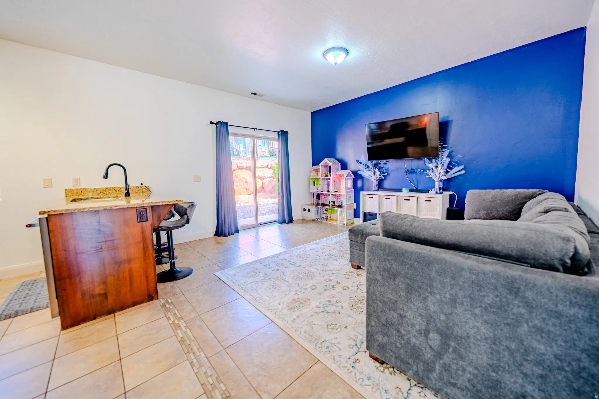 Living area featuring light tile patterned floors, an accent wall, and bar area