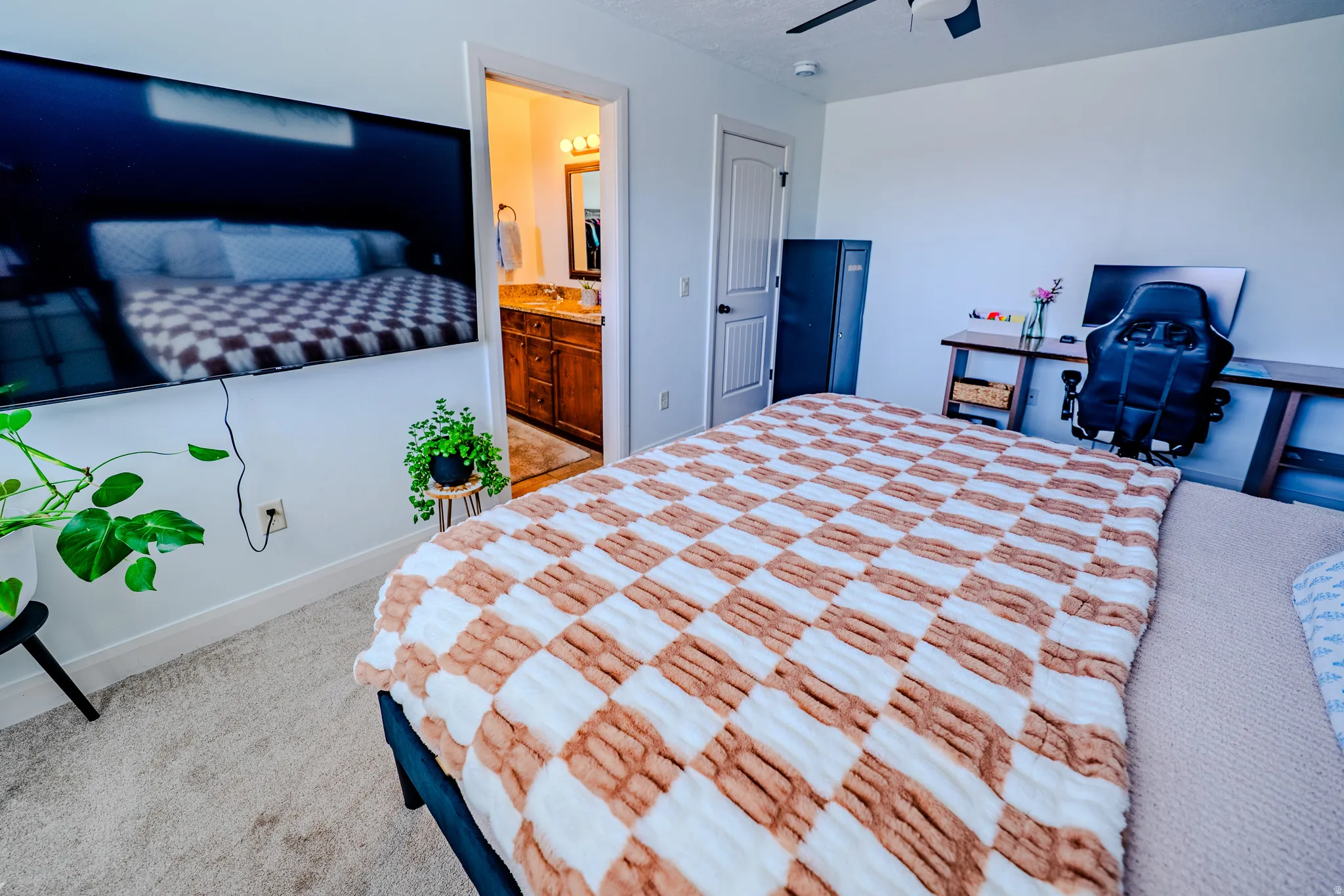 Bedroom featuring light carpet, ensuite bath, and ceiling fan
