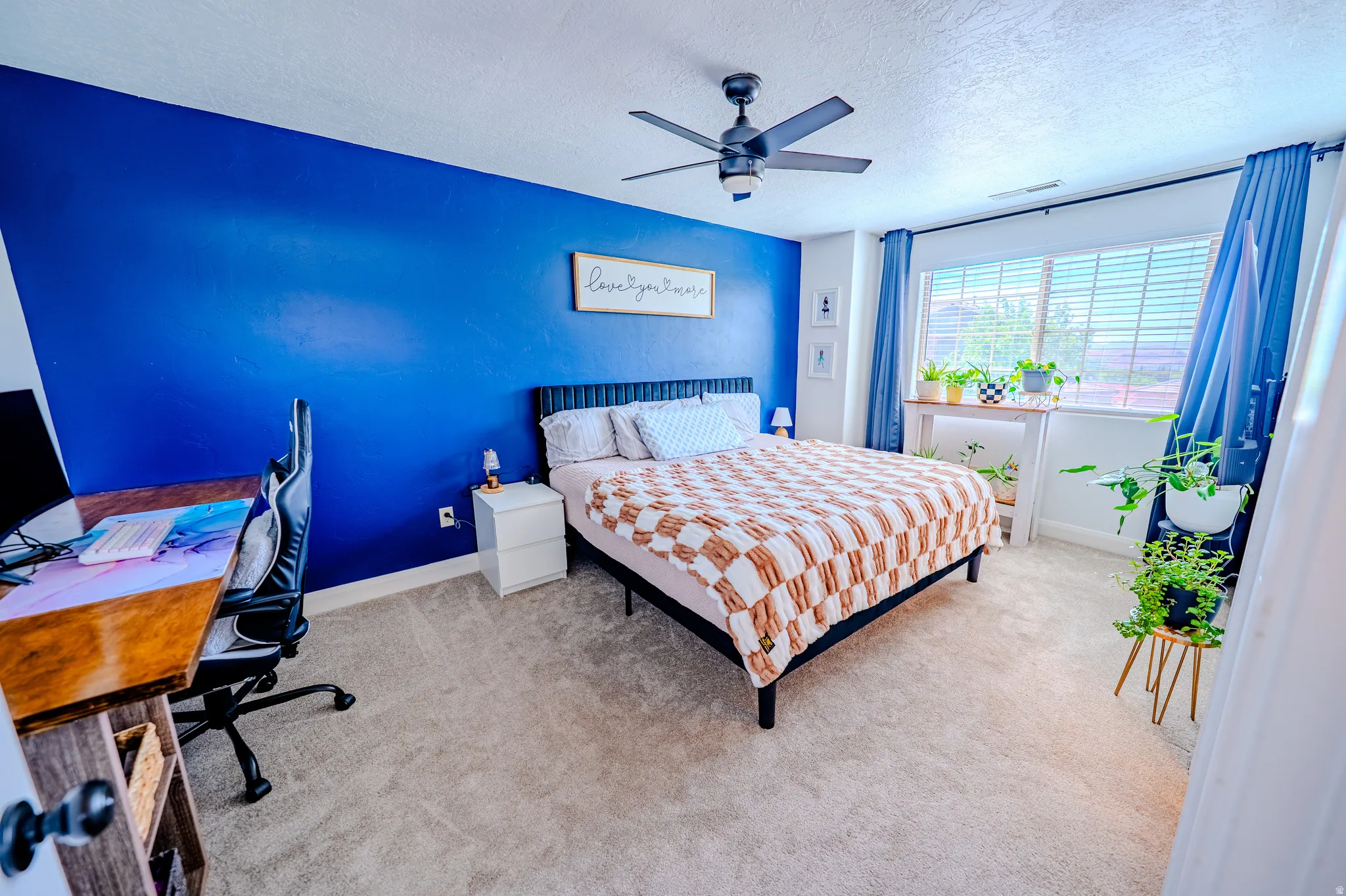 Bedroom with a desk, light carpet, a ceiling fan, and a textured ceiling