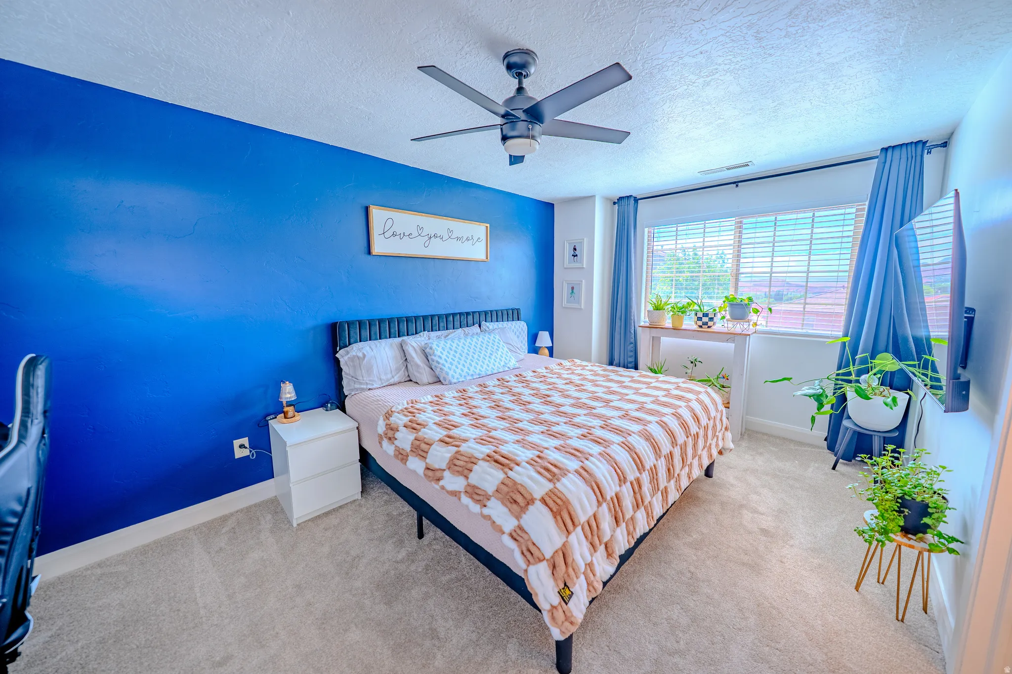 Carpeted bedroom featuring a textured ceiling and ceiling fan